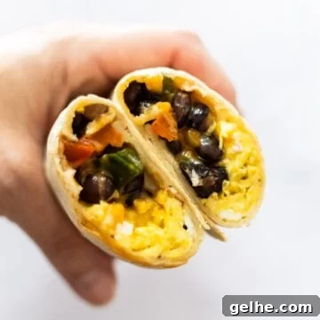 A side view of a halved breakfast burrito on a plate.