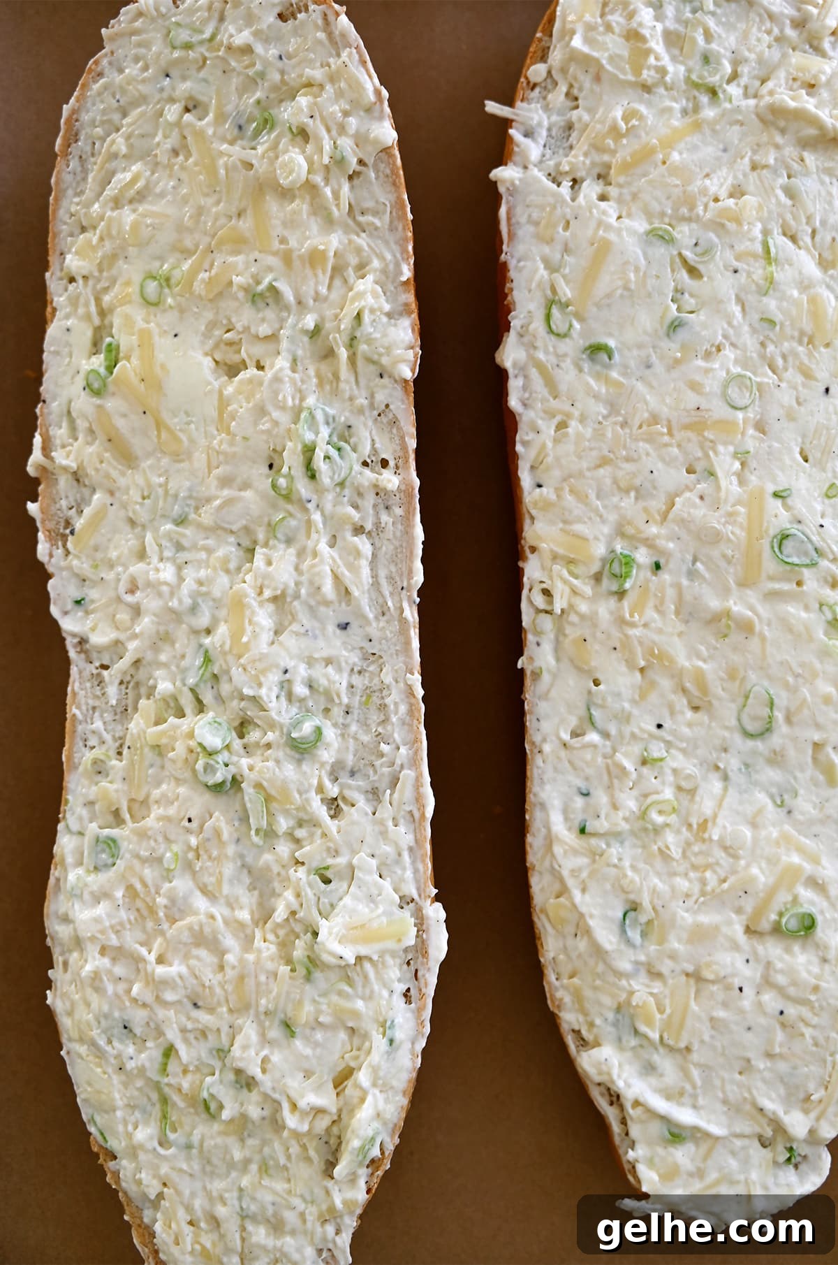A French loaf cut in half and slathered with a cheesy garlic butter spread.