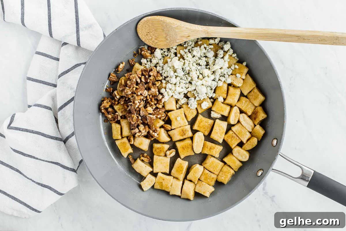 Gnocchi in skillet with walnuts and blue cheese crumbles.