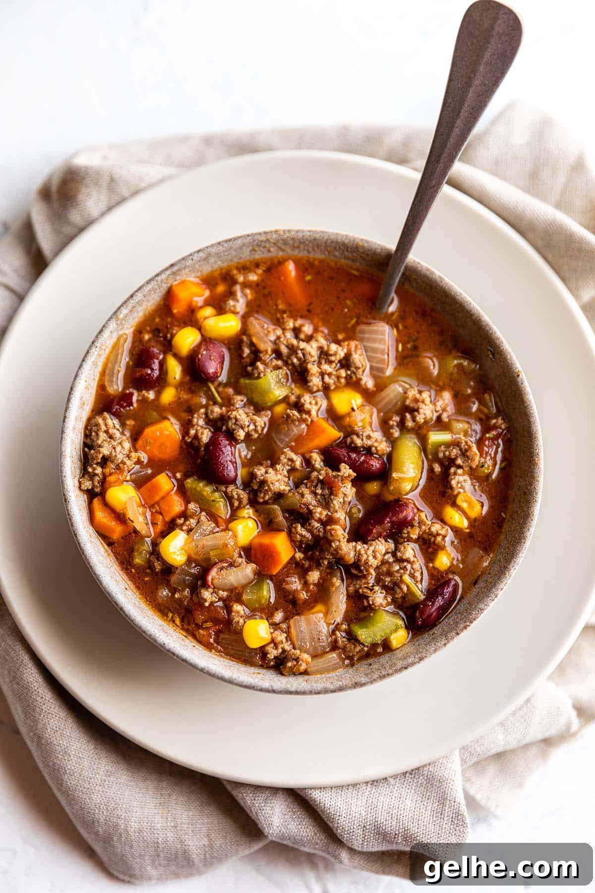 Hearty Ground Beef and Vegetable Soup Recipe 5 A bowl full of a soup that is green beans, corn, carrots, celery and ground beef.