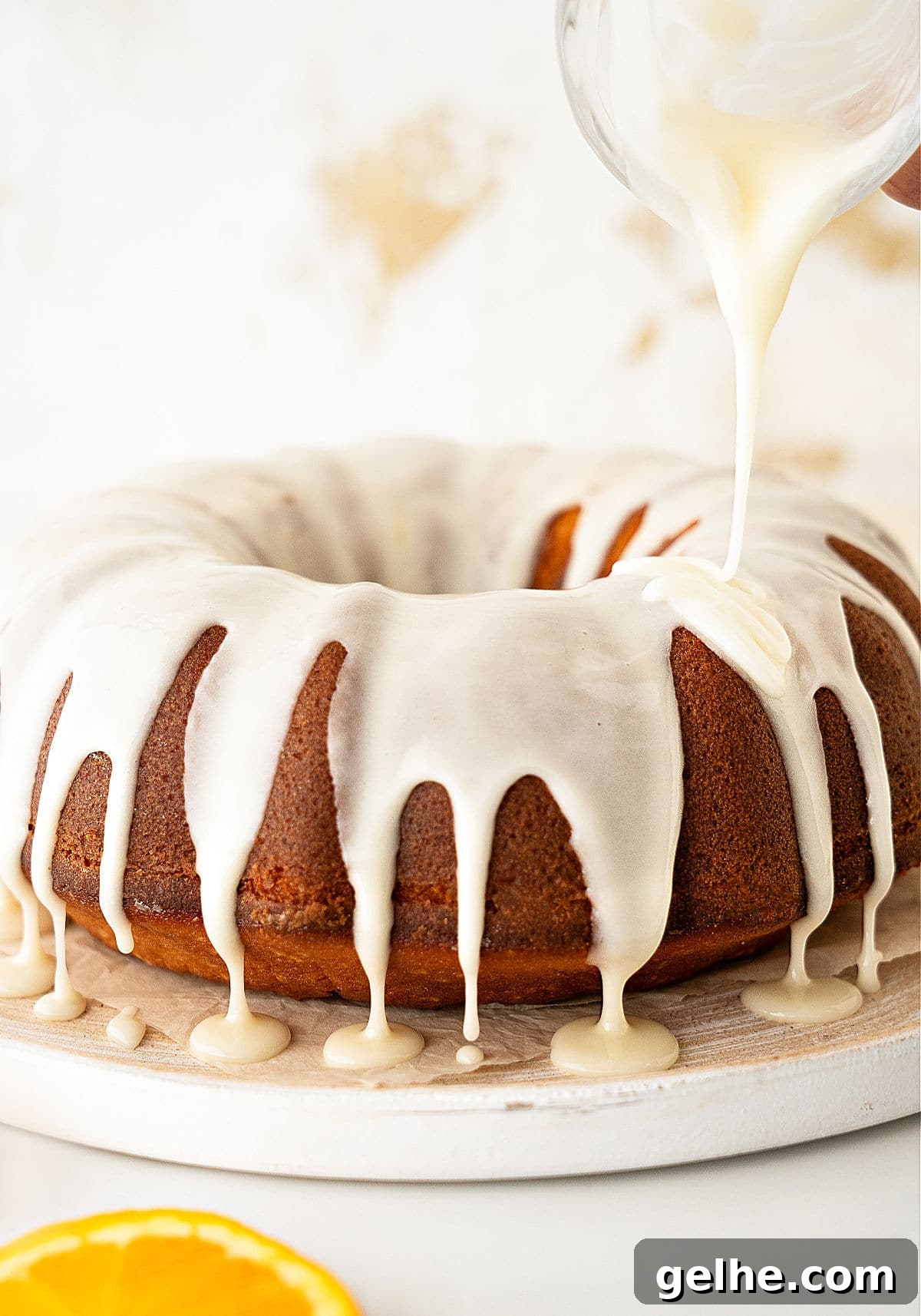 Glazing a bundt cake on a white plate. White background.