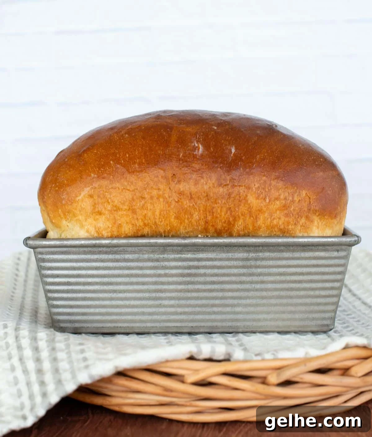 A golden loaf of white sandwich bread sits in a loaf pan.