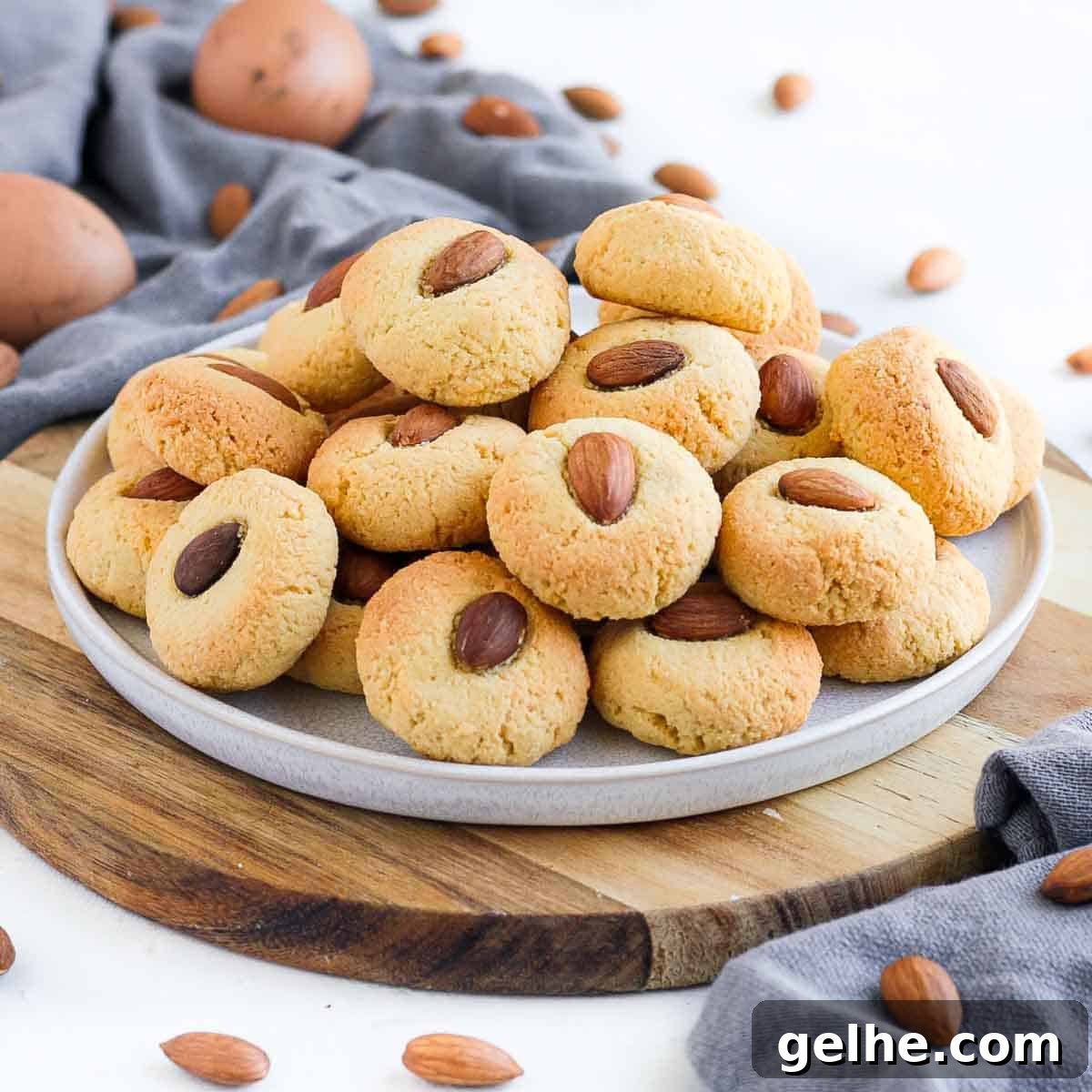 Stack of almond cookies on a white plate over a wooden board.