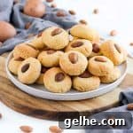 Stack of almond cookies on a white plate over a wooden board.