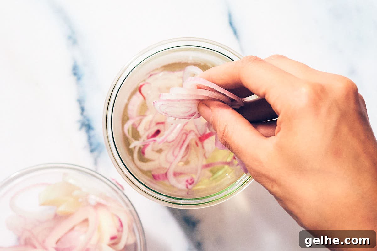 Thinly sliced shallots being added to vinegar brine to quick pickle.