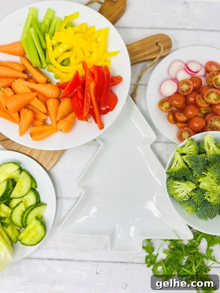 Image shows the ingredients needed to make a christmas tree crudite platter including; a plate of carrots, peppers and celery, a plate of cucumber, a plate of tomatoes and radish, a plate of broccoli