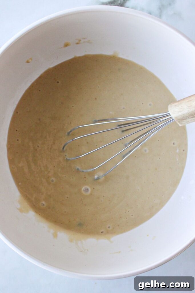 Wet ingredients for blueberry chocolate chip muffins combined in a white bowl with a whisk.