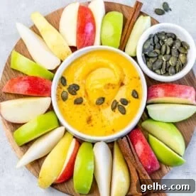 White bowl with pumpkin pie fruit dip surrounded by apple slices.