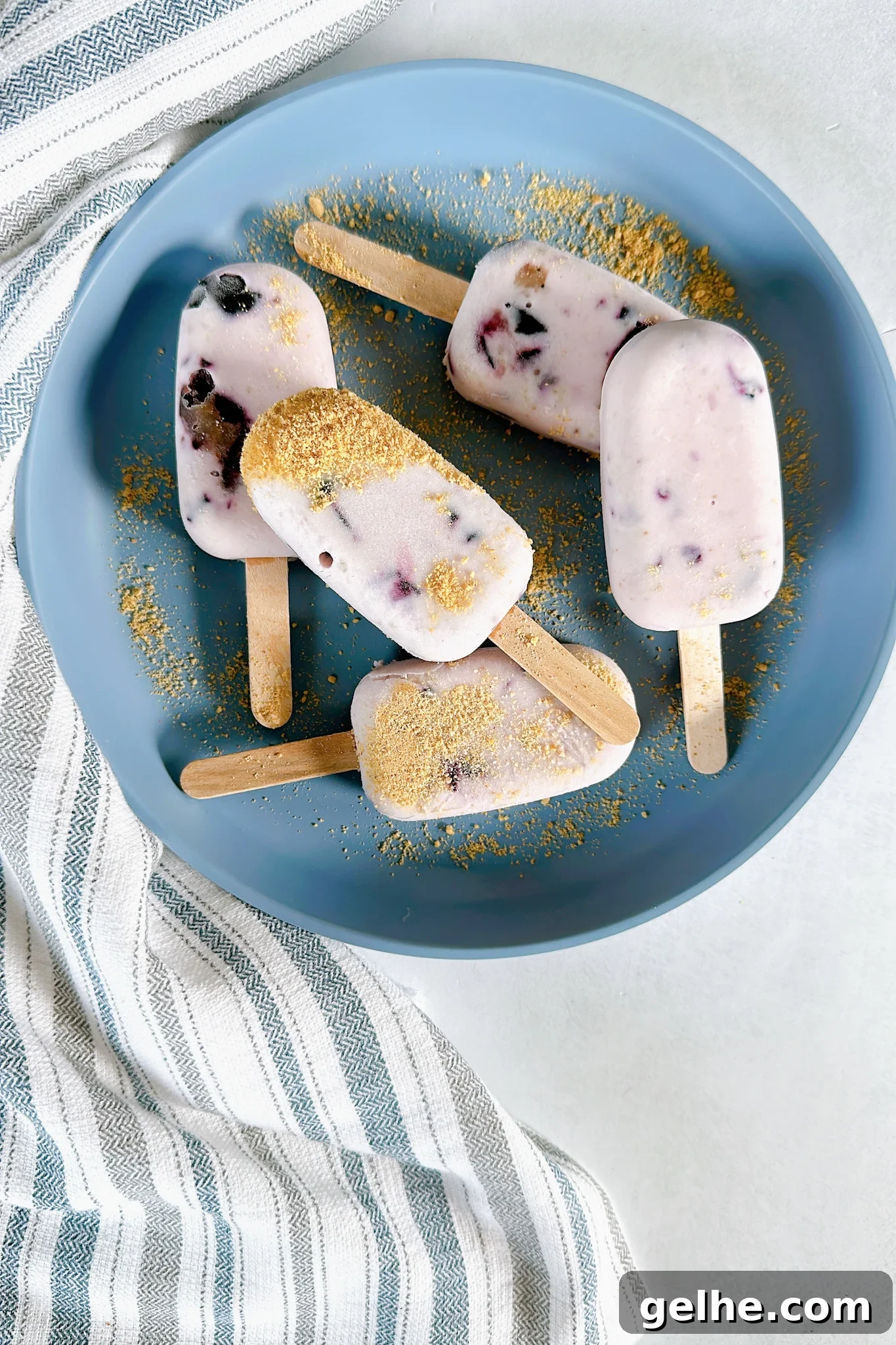 Mini blueberry cheesecake popsicles on a blue plate.