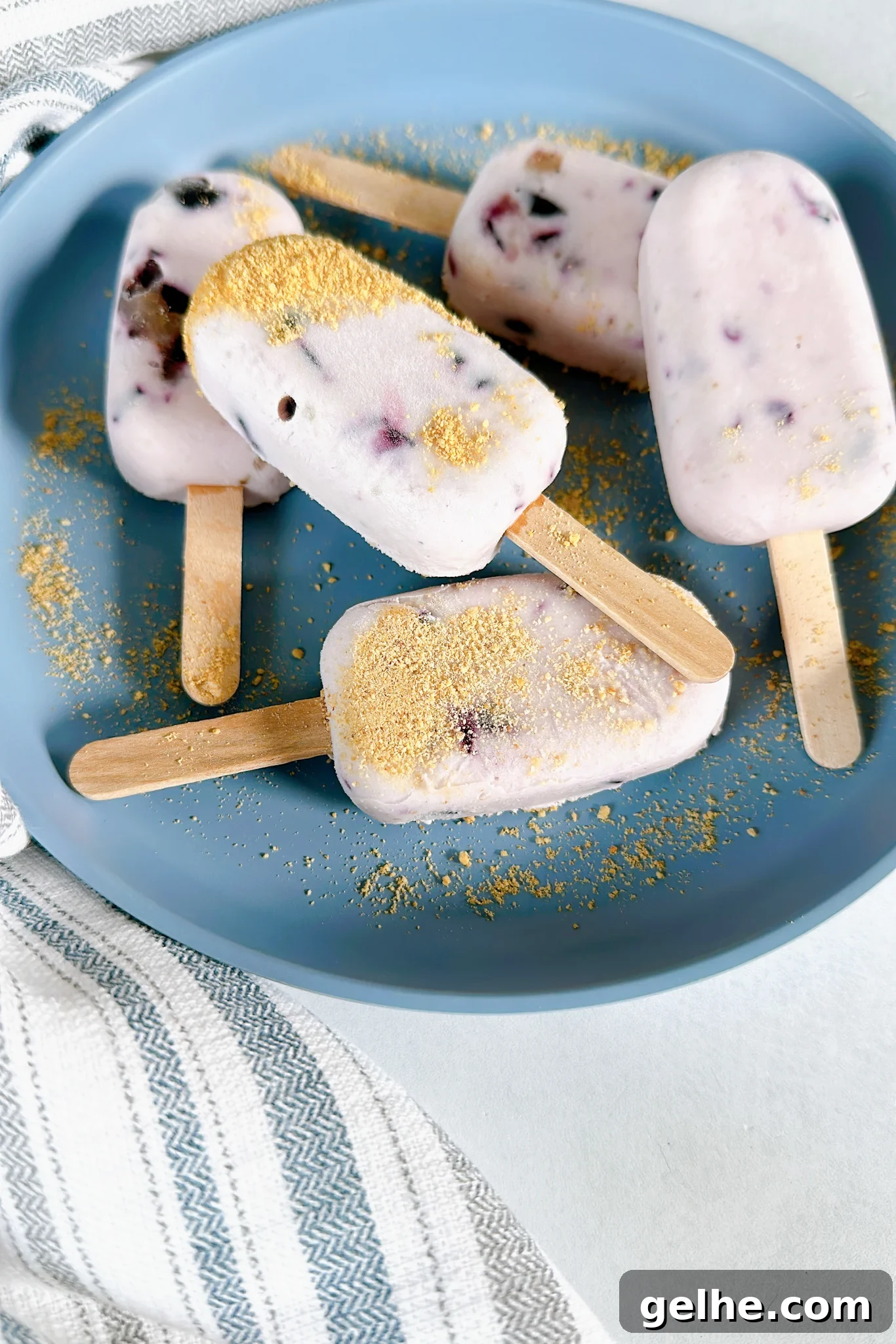 Mini blueberry cheesecake popsicles on a blue plate.