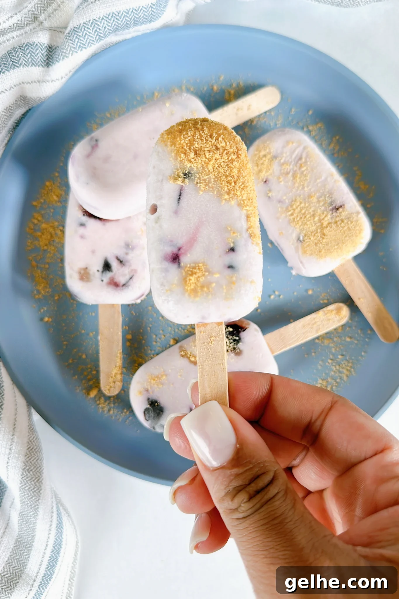 Mini blueberry cheesecake popsicles on a blue plate.