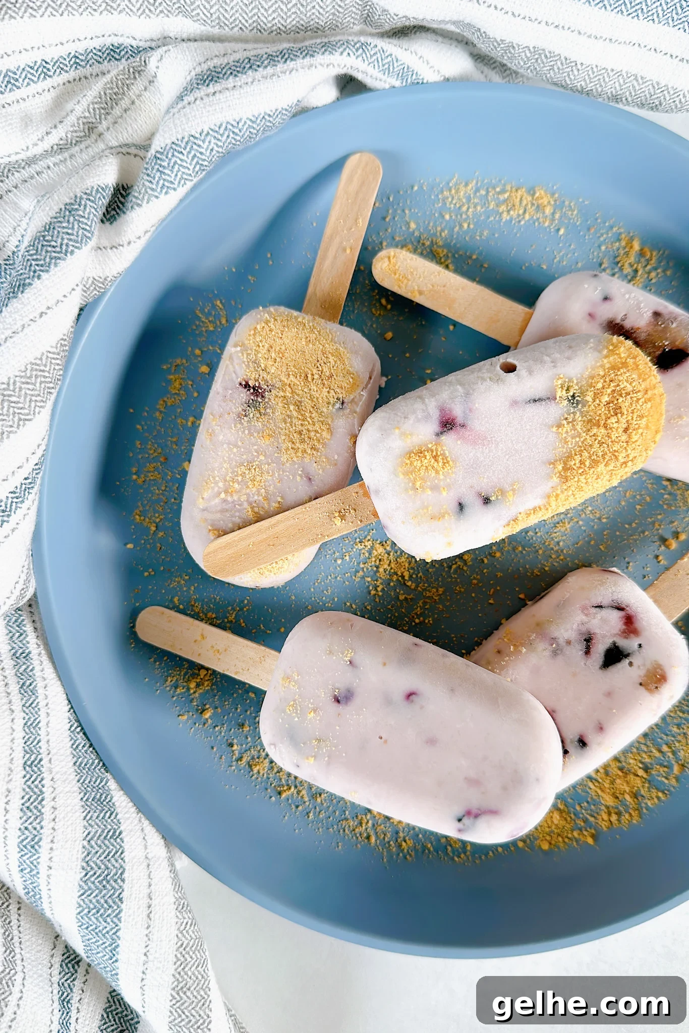 Mini blueberry cheesecake popsicles on a blue plate.
