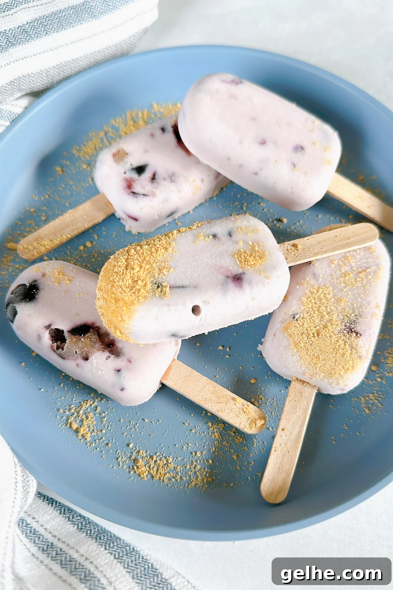 Mini blueberry cheesecake popsicles on a blue plate.