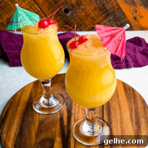 Two frozen Mai Tai slushies in curvy hurricane glasses, each garnished with cherries and colorful umbrellas, placed on a round wooden board.