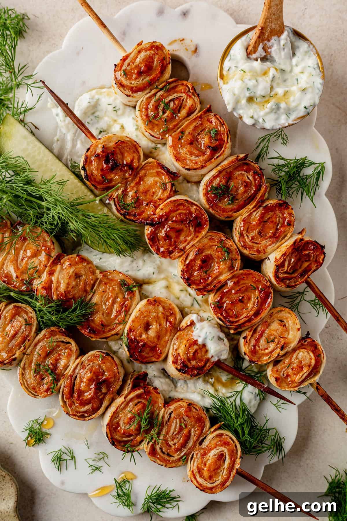 4 lazy kebab rolls on a platter with tzatziki sauce on the side.