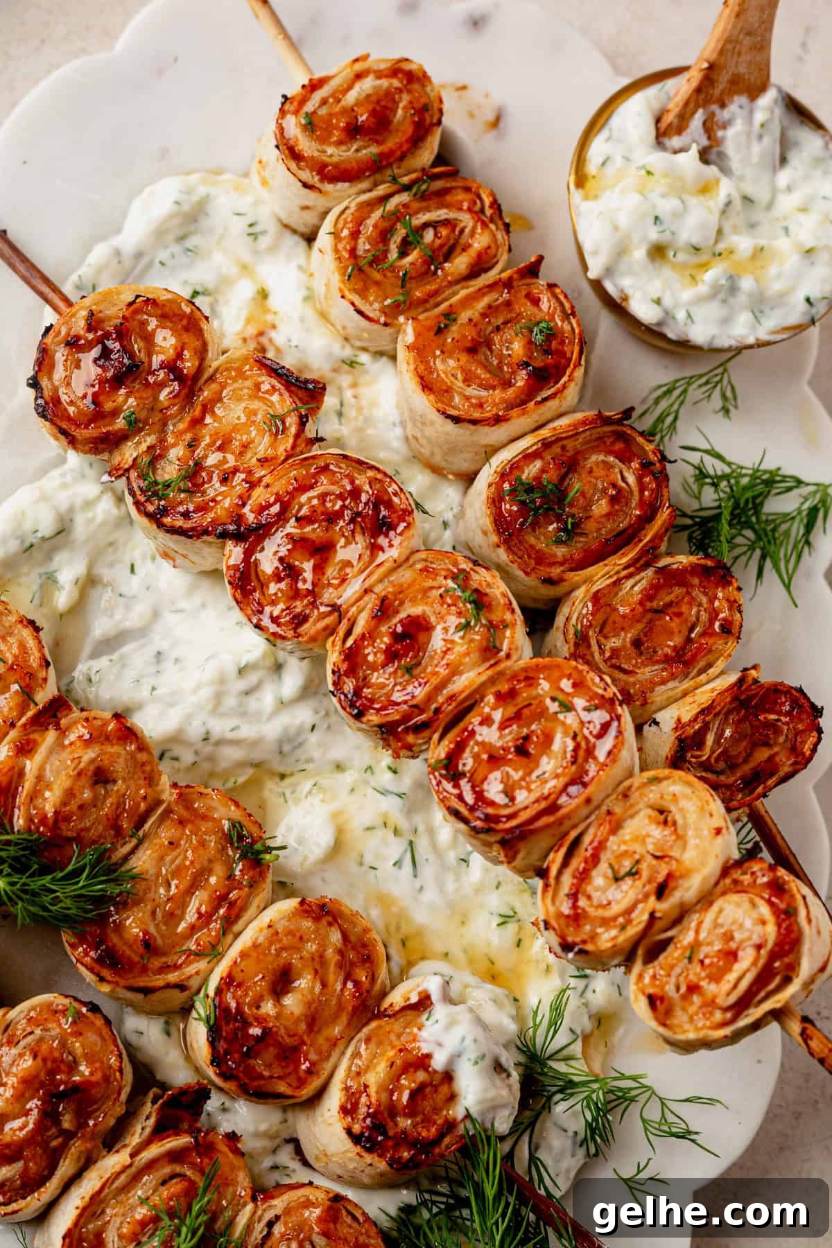 a lazy ground chicken kebab roll on a platter with a side of homemade tzatziki sauce.