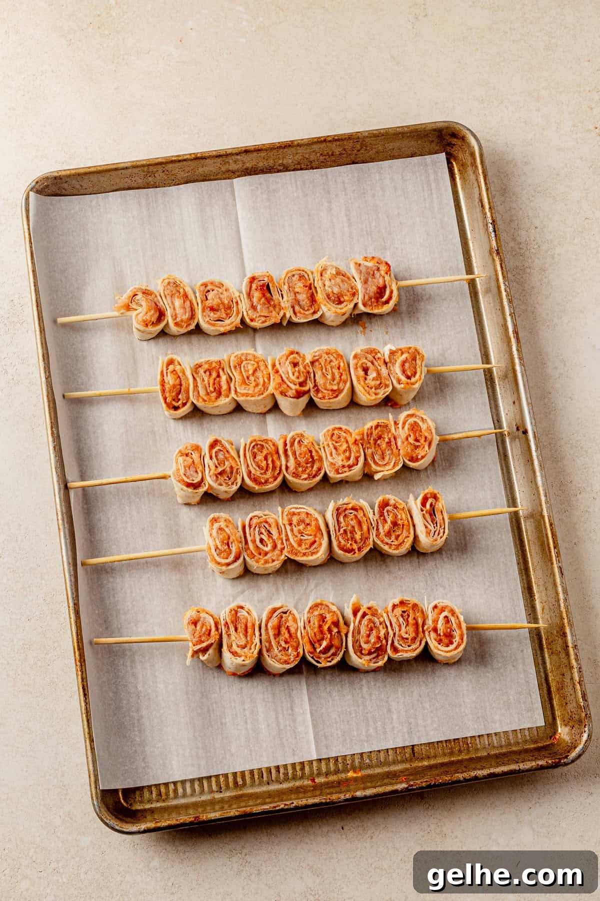 lazy kebab rolls on skewers on a sheet pan before baking.