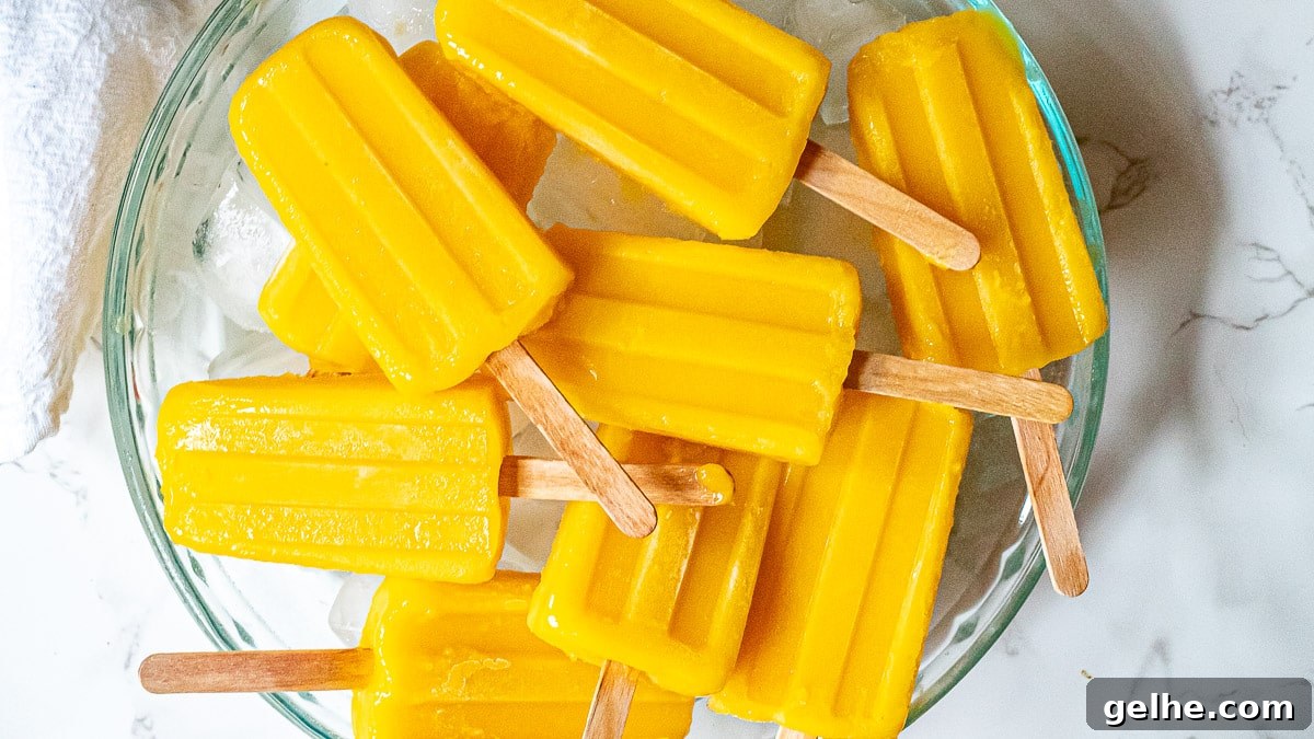 Homemade Mango Popsicles Recipe — Refreshing Summer Treat 4 mango popsicles on a tray with ice