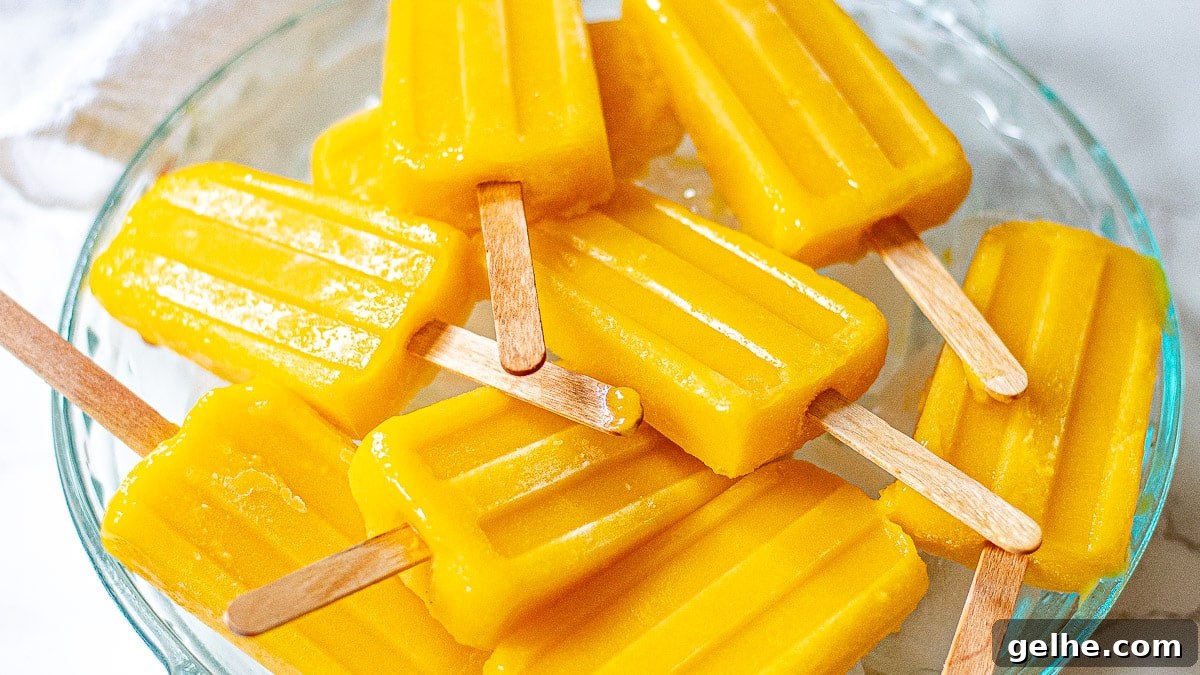 Homemade Mango Popsicles Recipe — Refreshing Summer Treat 5 mango popsicles on a tray with ice