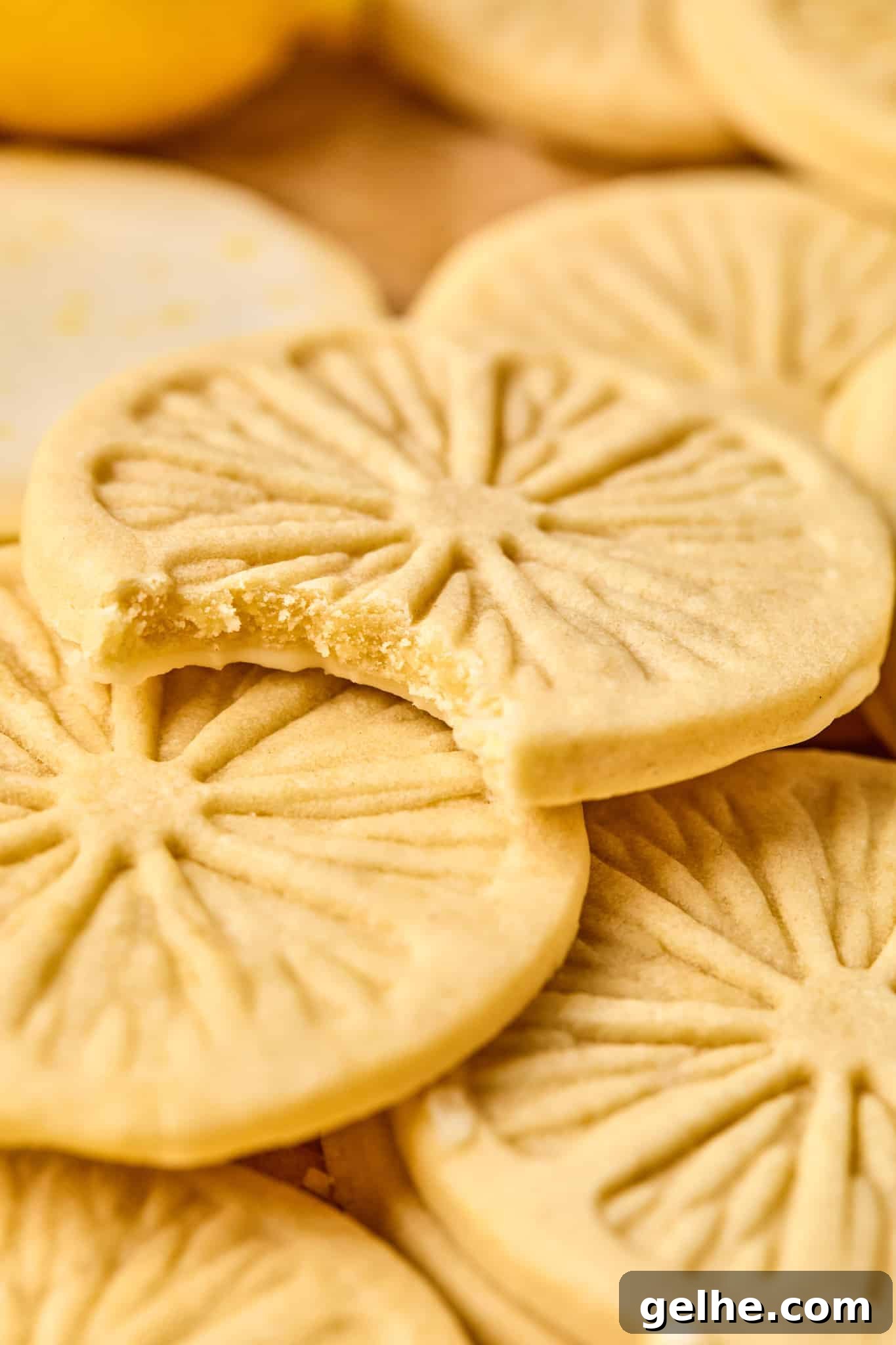 Homemade Girl Scout Lemonade Recipe: Refreshing Copycat Version 2 Lemonade cookies piled on top of each other and the top cookie has a bite taken out of it showing the inside of the cookie.