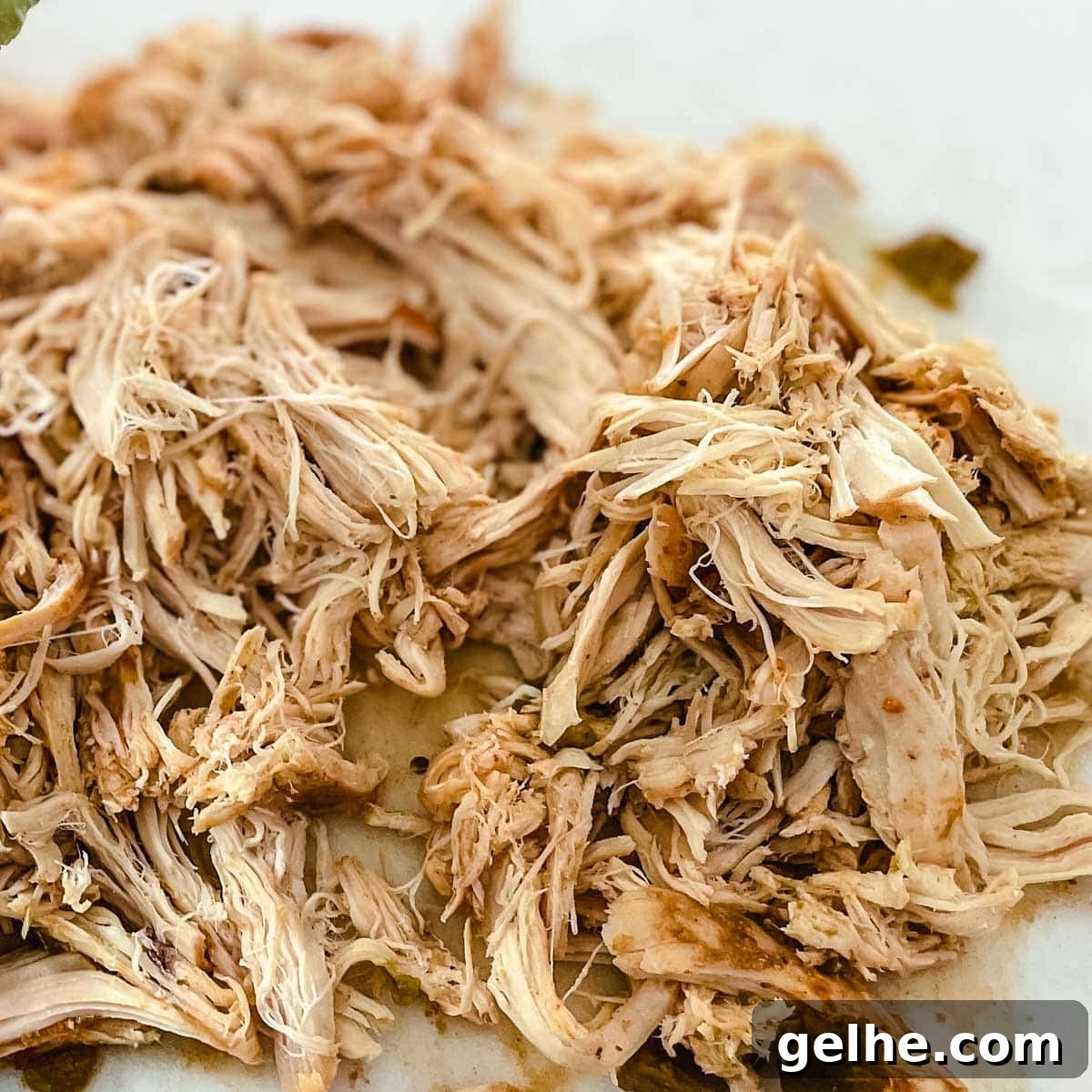 Slow Cooker Shredded Chicken Enchiladas Recipe 8 Shredded chicken sits on a white cutting board.