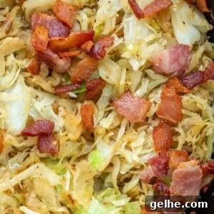 a cast iron skillet full of fried cabbage and crispy bacon with tender onions