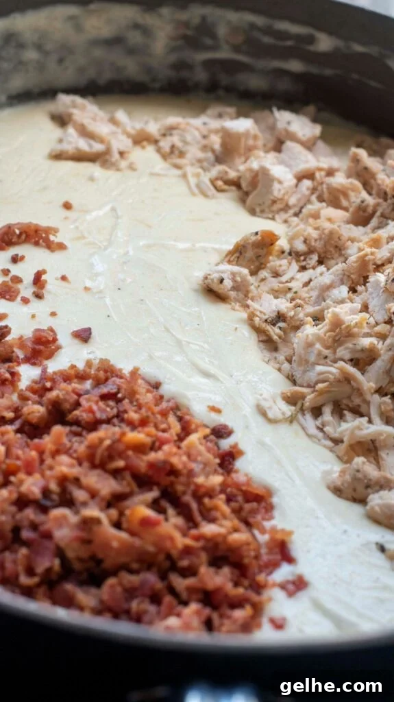 bacon and chicken with alfredo sauce in a pan