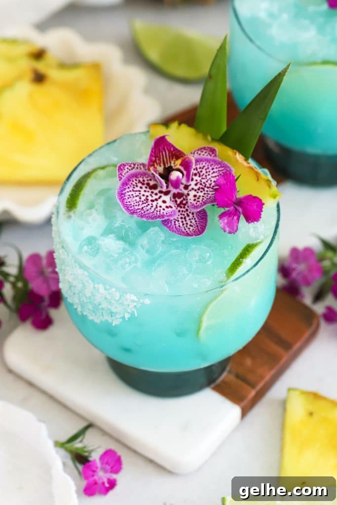 virgin blue hawaiian drink topped with purple flowers and fresh pineapple