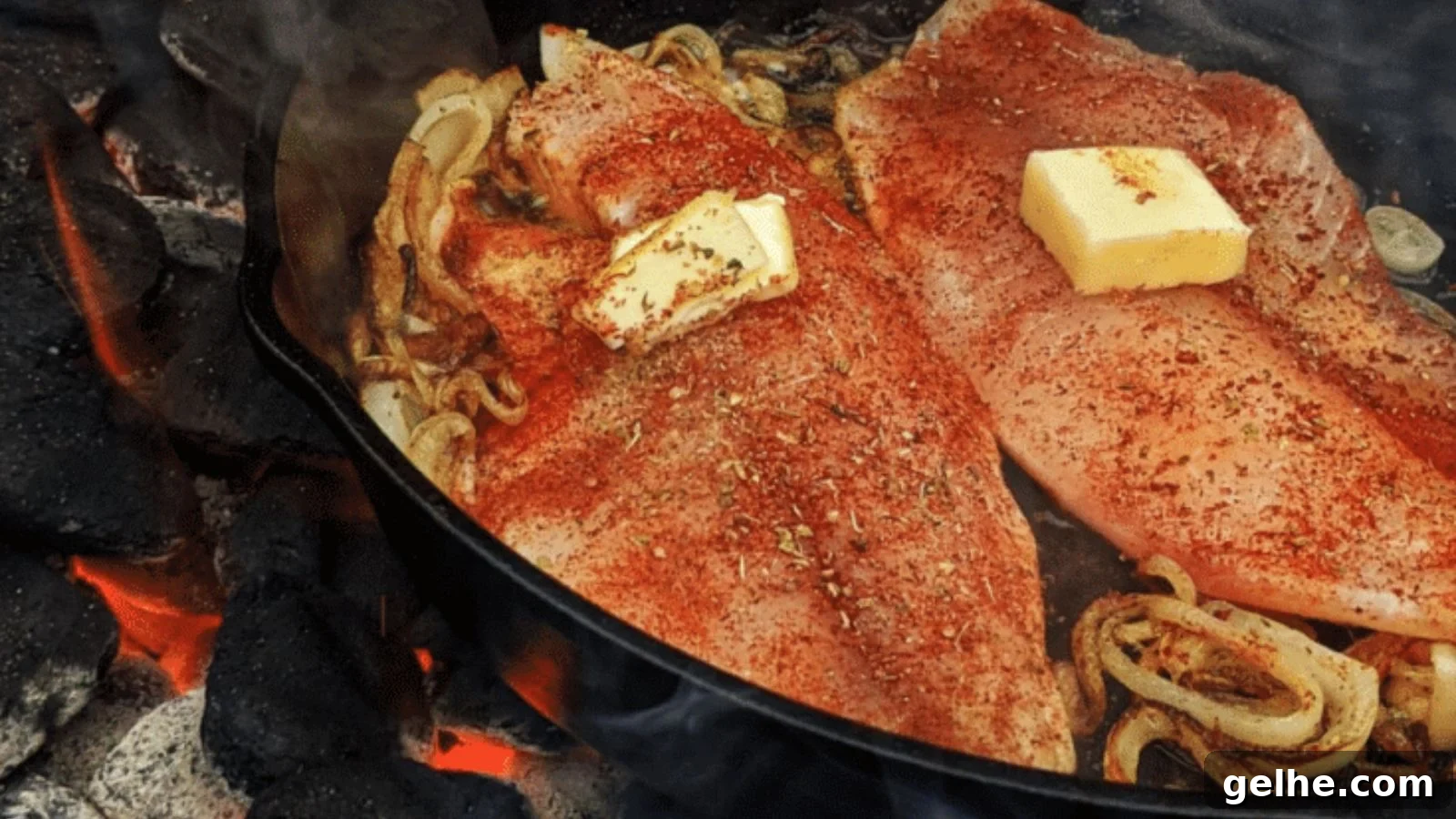 Tilapia grilled over charcoal with dark grill marks and lemon wedges beside it.