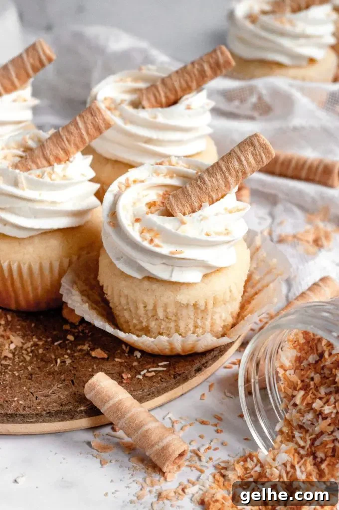 Light golden coconut cupcakes topped with white whipped cream cheese frosting with some toasted coconut sprinkled on top.