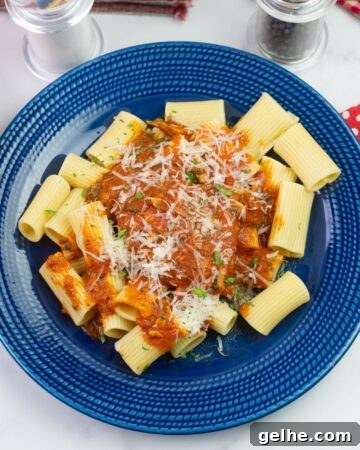 Instant Pot Chicken Marinara served over rigatoni pasta on a dinner plate.