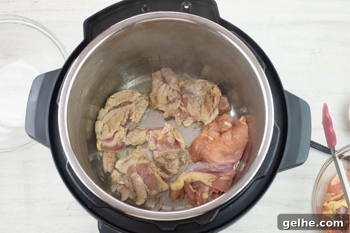 Browning seasoned chicken thighs in the Instant Pot.