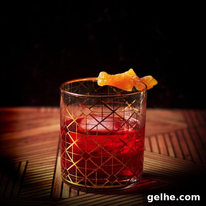 A Boulevardier cocktail, served in a cocktail glass over ice and garnished with an orange twist.