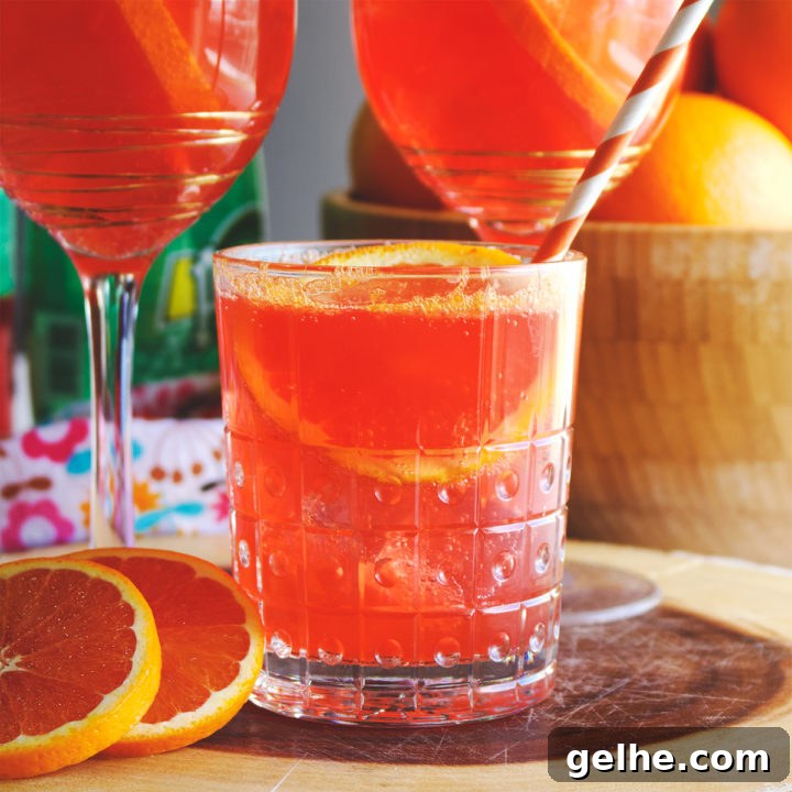 A wood tray with three glasses filled with Aperol Spritz. Fresh oranges surround the glasses.