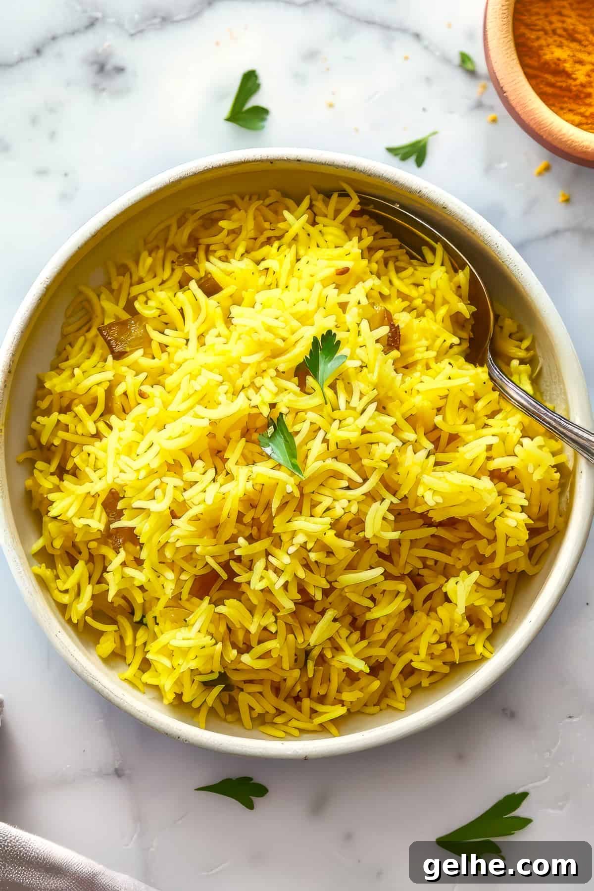 Pilau rice in a white bowl with a spoon.
