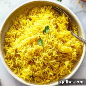 Pilau rice in a white bowl with a spoon.