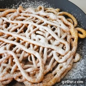 State fair funnel cake on black plate with white powdered sugar.