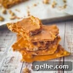 Soft peanut brittle stacked on top of each other with a pan of the rest of the brittle in the background.