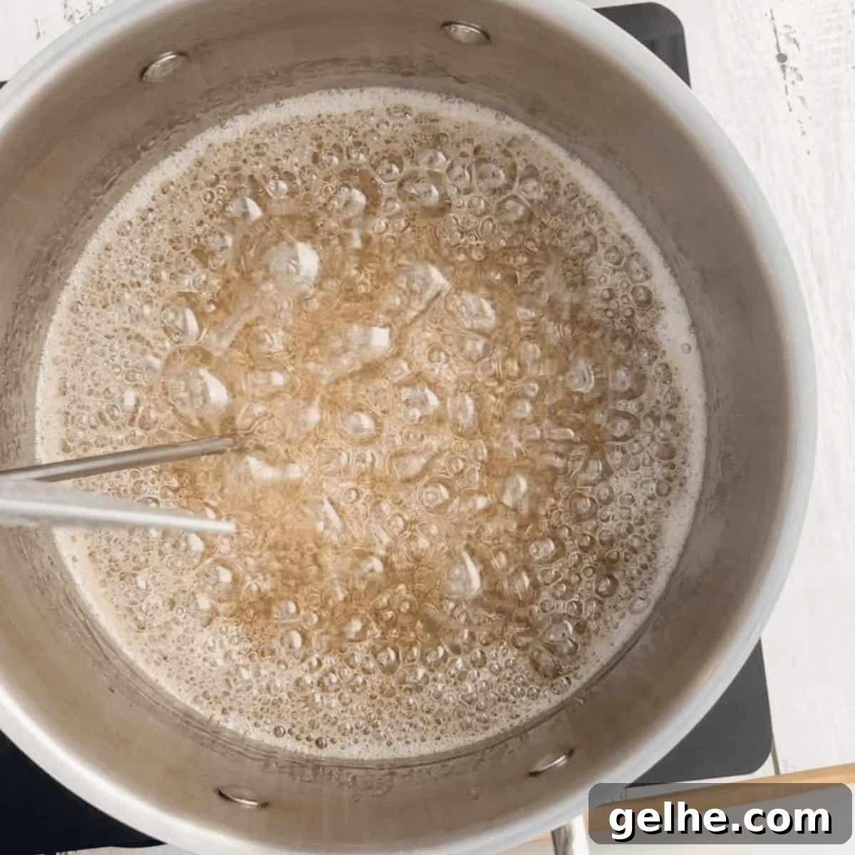 The sugar mixture boiling in a large pot with a candy thermometer on the side.