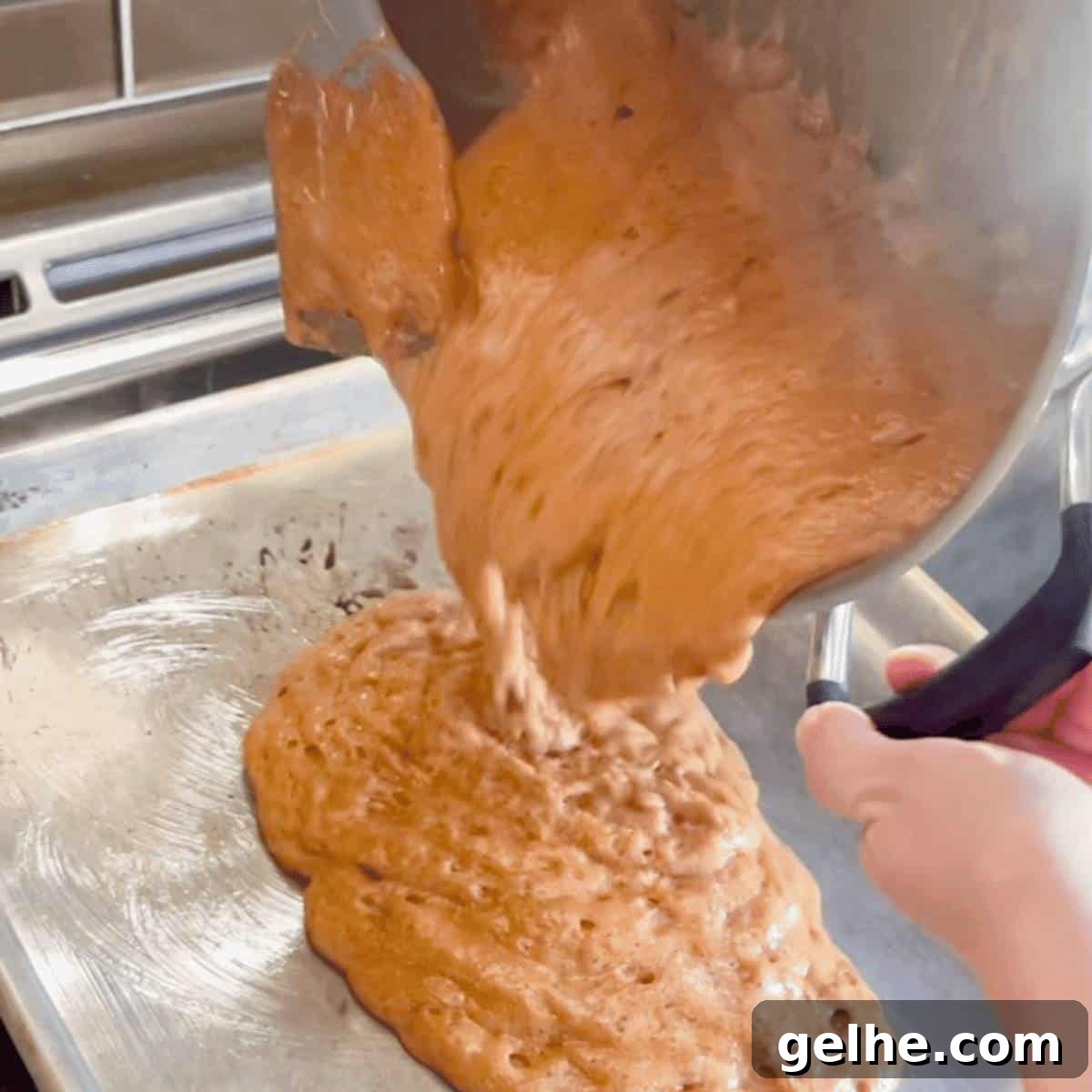 The foaming mixture being poured onto a greased cookie sheet with a rim.