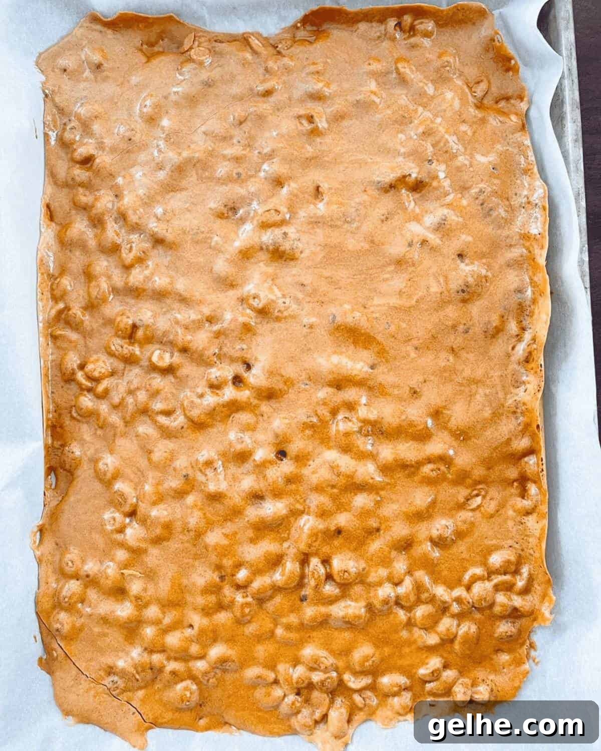 The peanut brittle mixture poured onto a baking sheet with parchment paper.