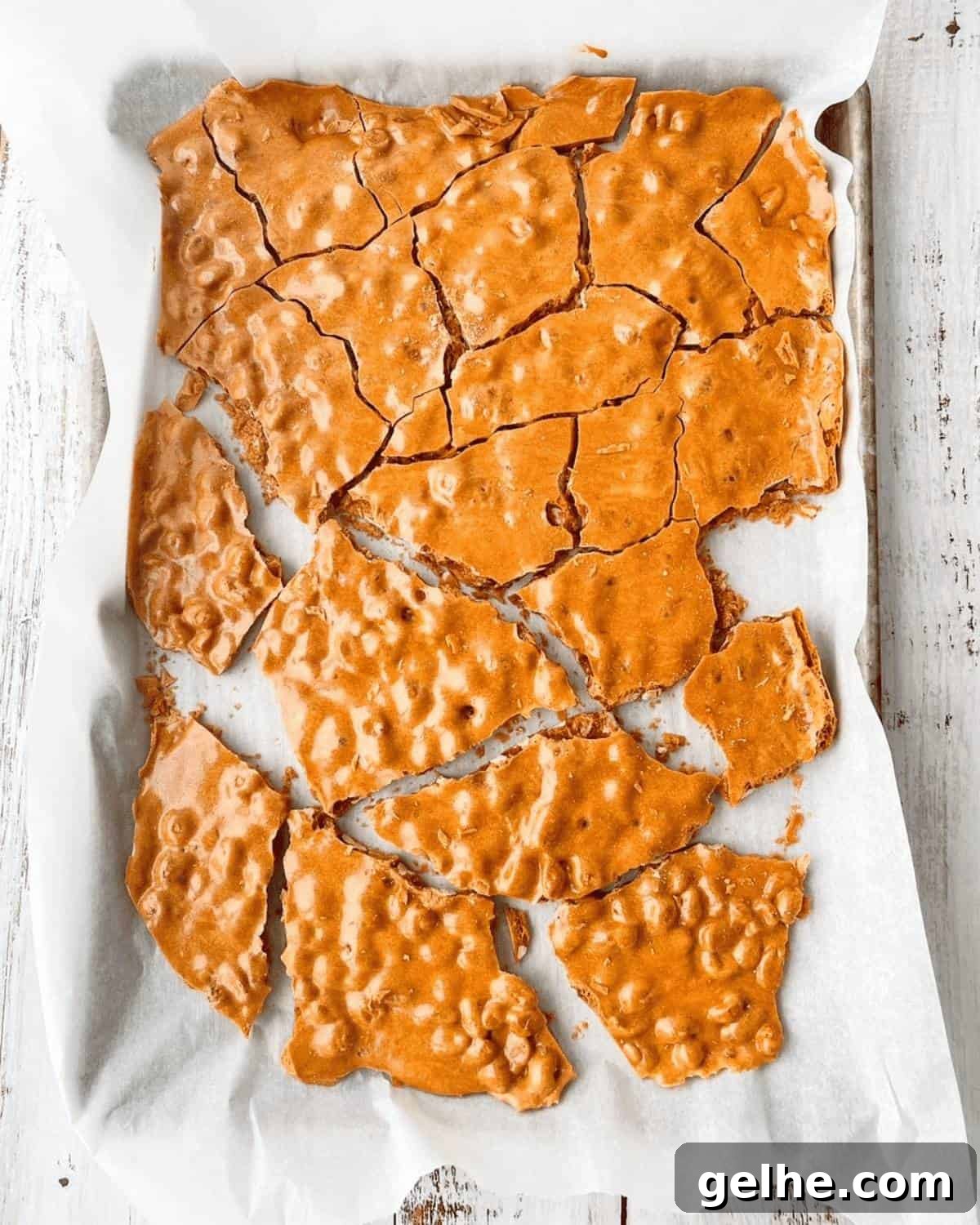 The cooled soft peanut brittle broken into large pieces on a baking sheet.