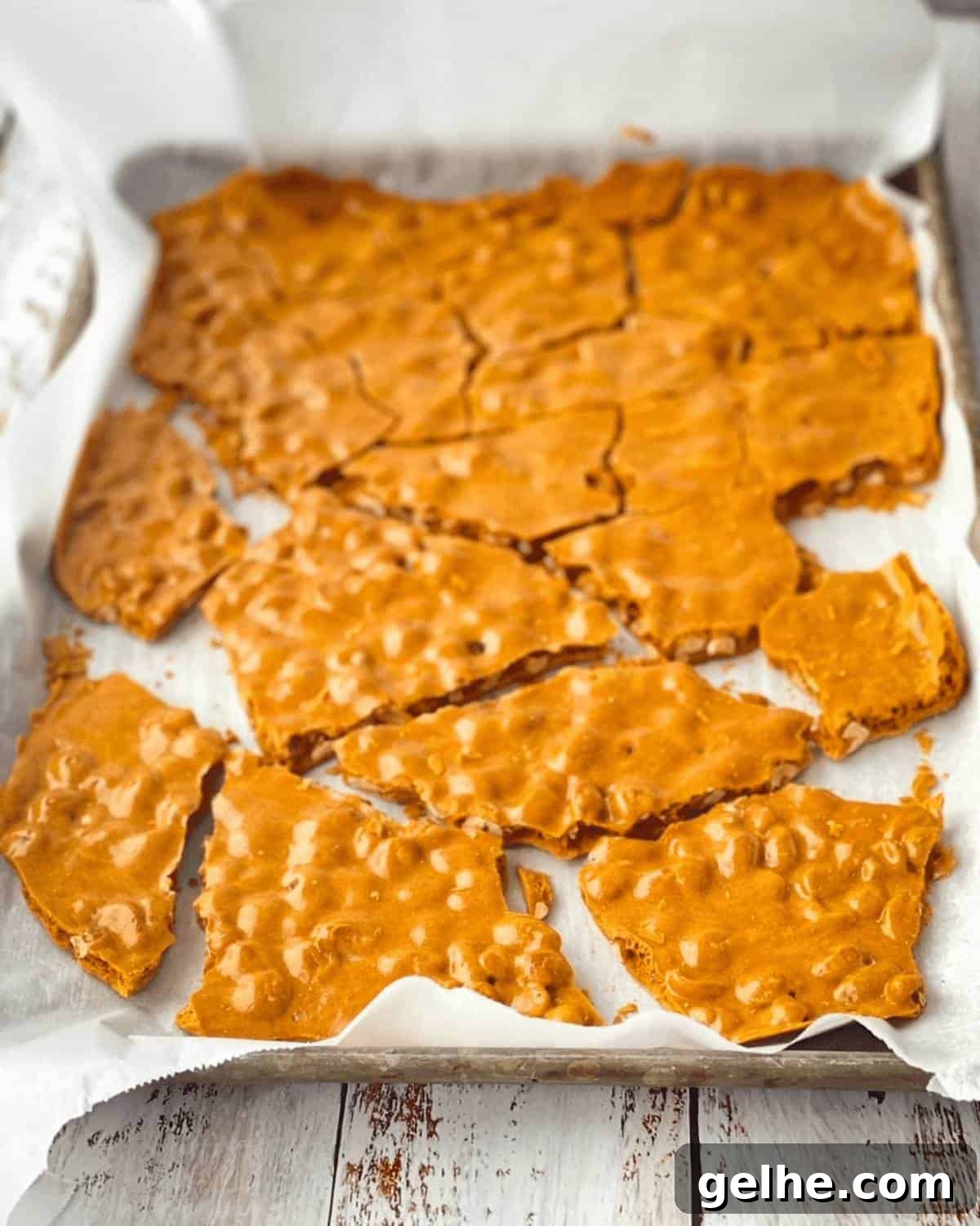 Soft peanut brittle broken into large pieces for serving on a baking sheet lined with parchment paper.