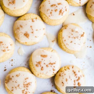 Soft pumpkin cookies with icing on a piece of parchment paper.