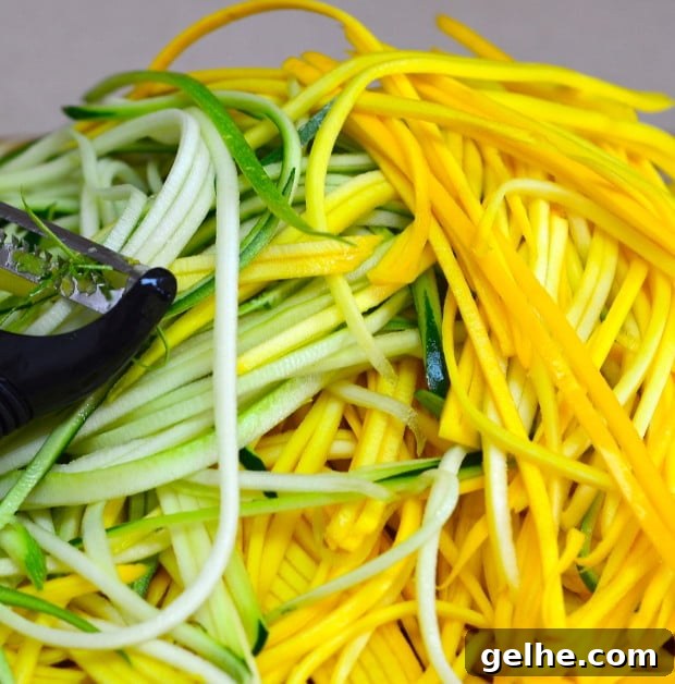 A pile of zucchini noodle next to a julienne peeler