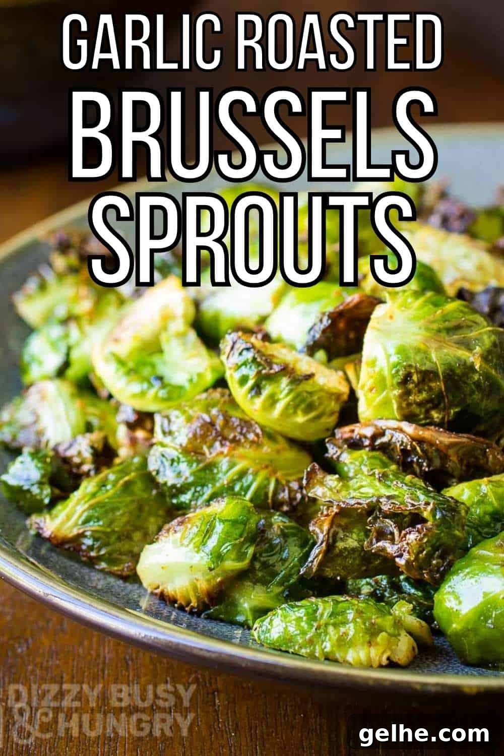 Side shot of garlic roasted Brussel sprouts on a blue and grey plate on a wooden table.