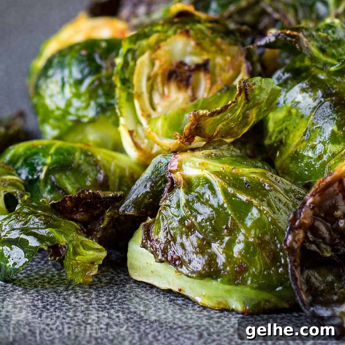 Close up view of garlic roasted Brussel sprouts on a blue and grey plate.