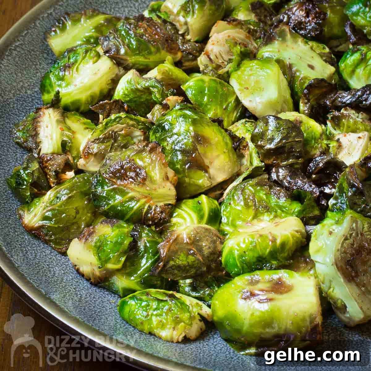 Side angled shot of garlic roasted Brussel sprouts on a blue and grey plate.