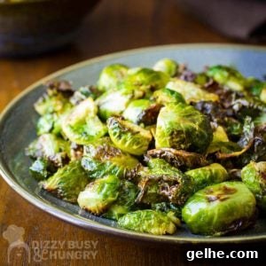 Side shot of garlic roasted Brussel sprouts on a blue and grey plate on a wooden table.