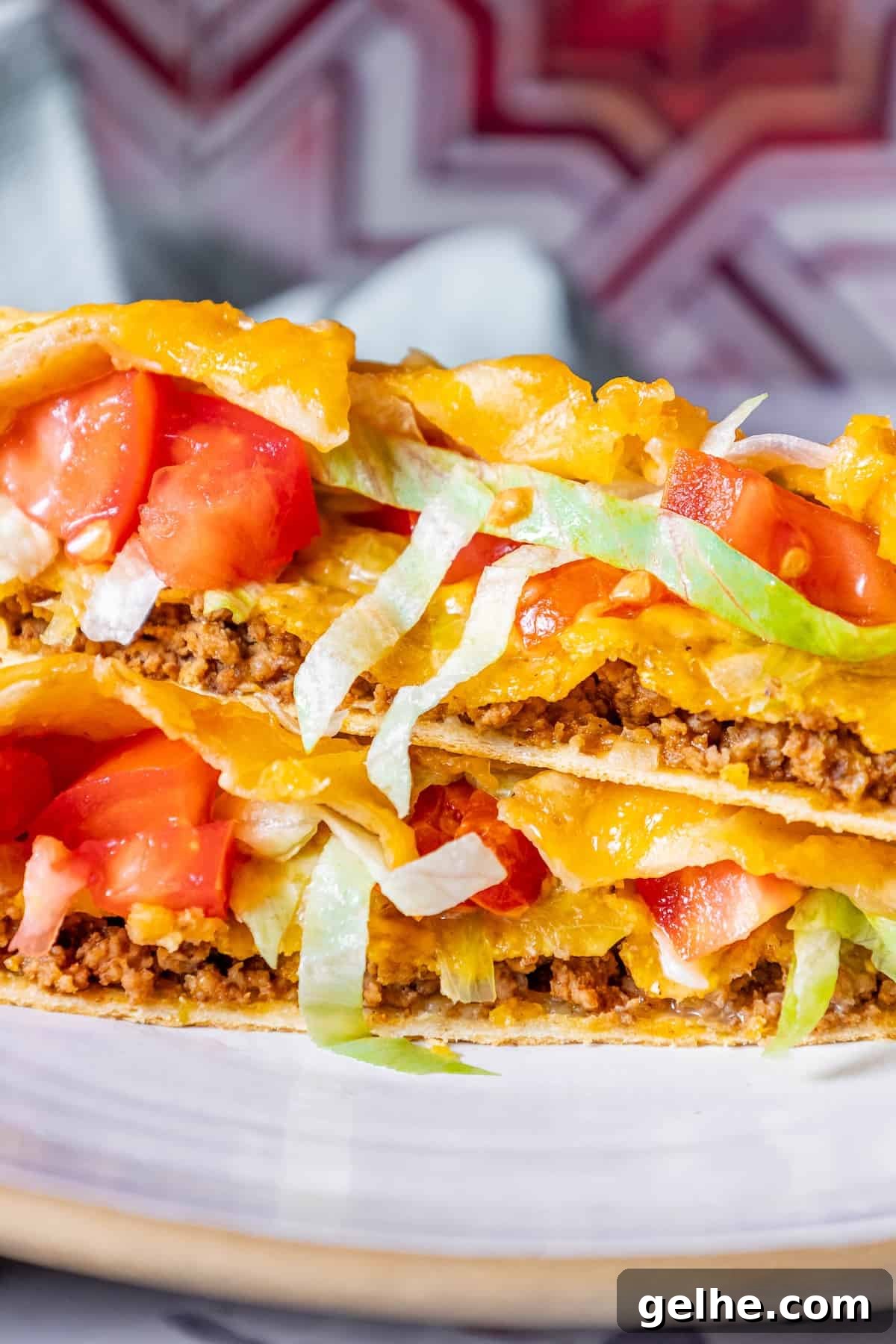 Crispy Homemade Crunchwrap Recipe: Copycat Taco Bell Wrap 2 A stack of CrunchWrap tacos on a plate with tomatoes and lettuce.